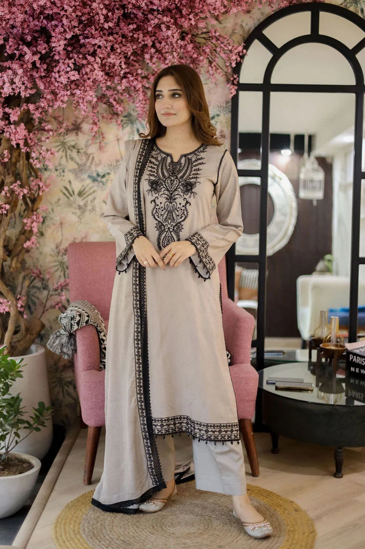 Woman in an embroidered outfit standing in a decorated room with pink flowers and a mirror.