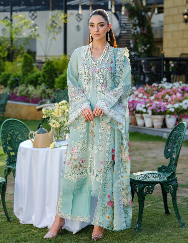 Woman in a light blue embroidered outfit standing. Lawn Embroidered Dress for Summer 2026