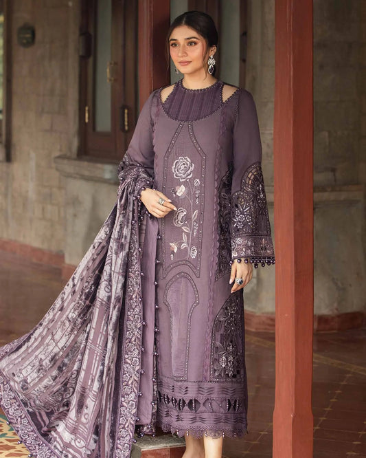 Woman in a purple embroidered outfit standing indoors with a decorative patterned floor.